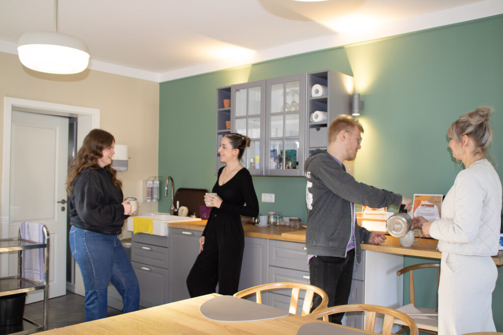 Menschen im Gespräch und beim gemeinsamen Kochen in der Begegnungsküche Pottkieker des AFZ Friedland.