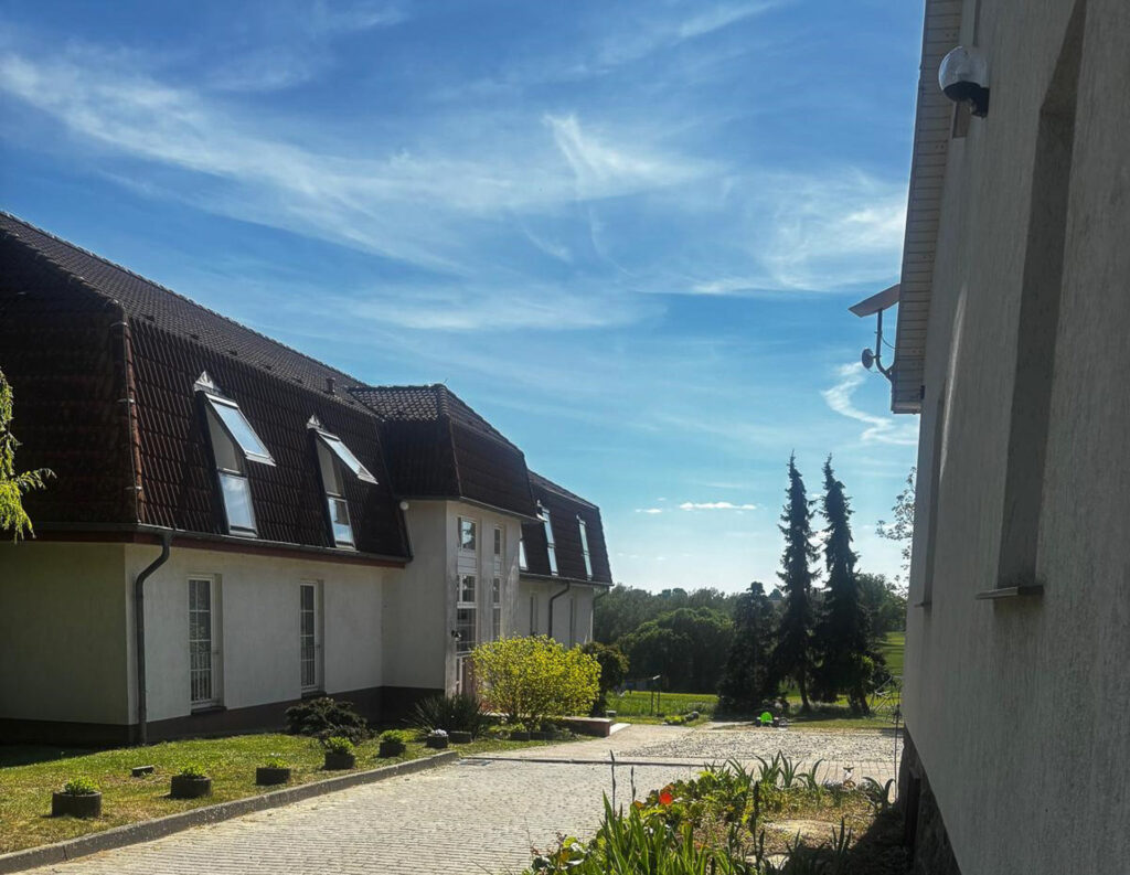 Außenansicht der Flüchtlingsunterkunft Göhren mit Wohngebäude, Zufahrt und Grünanlage.